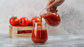 Hand pouring tomato juice in a glass cup. High quality photo