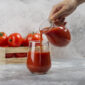 Hand pouring tomato juice in a glass cup. High quality photo
